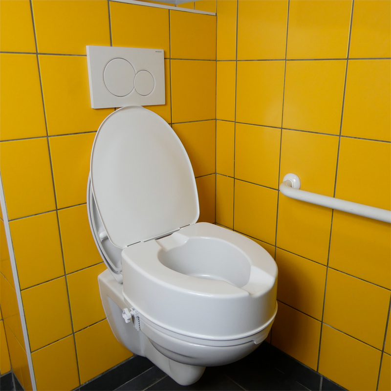 Réhausse WC Ibiza avec couvercle installée sur des toilettes à côté d'une barre d'appui - réf. 81109