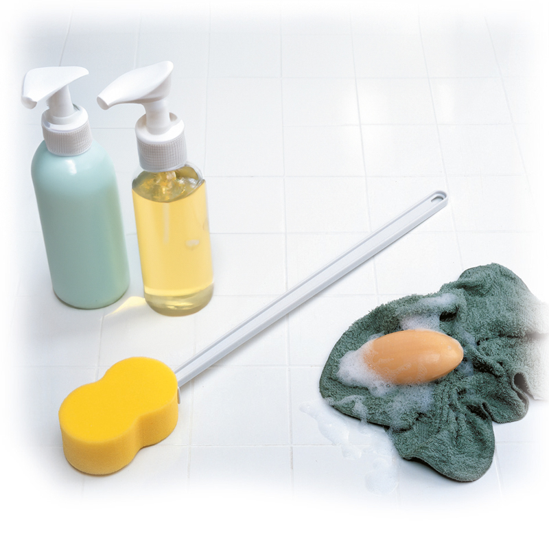 Éponge à manche anatomique en situation avec savon et flacons de toilette - réf. 812079
