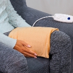 Femme assise avec le coussin chauffant électrique sur la cuisse