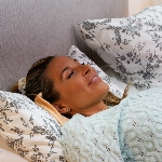 Personne allongée avec le coussin chauffant électrique sous la nuque
