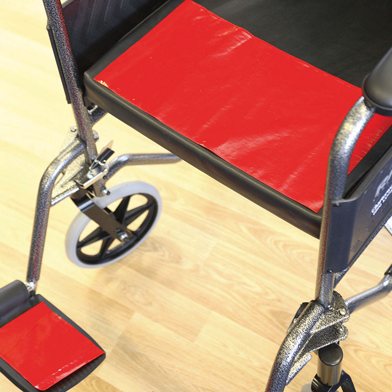 Antidérapant Dycem rouge appliqué sur l'assise et le repose-pied d'un fauteuil roulant