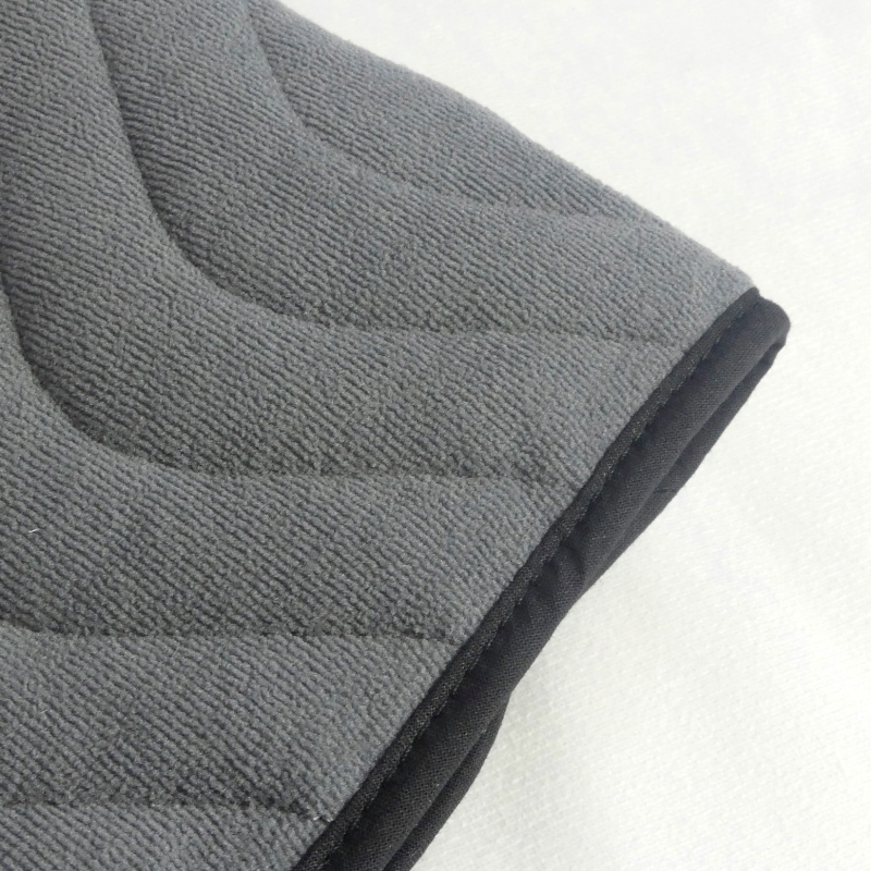 Gros plan sur la texture matelassée et le biais noir de la protection pour fauteuil