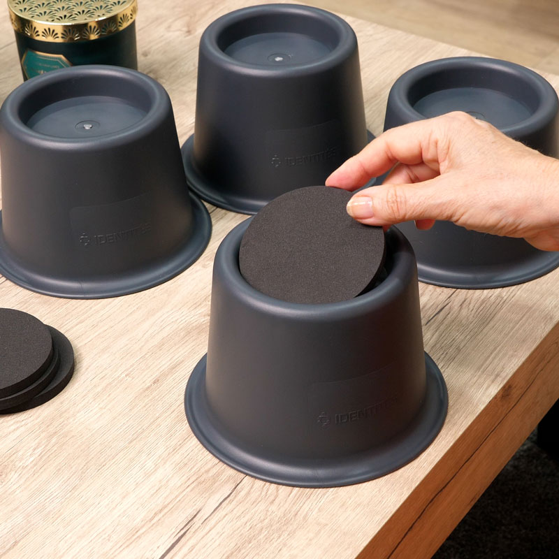 Set de 4 surélévateurs Resist avec disque antidérapant, installation facile sous meubles.