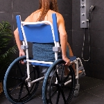 Femme assise dans une douche sur la chaise de douche et WC Aston grandes roues, vue de dos - réf. 82