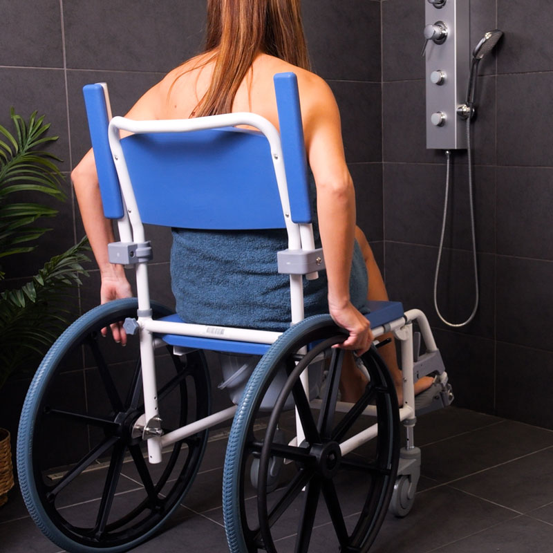 Femme assise dans une douche sur la chaise de douche et WC Aston grandes roues, vue de dos - réf. 82