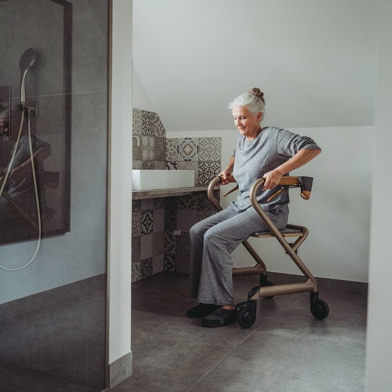 Femme assise sur le rollator d'intérieur Saljol dans une salle de bain - réf. 826307BL