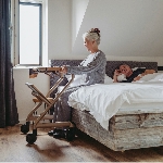 Femme assise au bord du lit en s'appuyant sur le rollator d'intérieur Saljol - réf. 826307BL