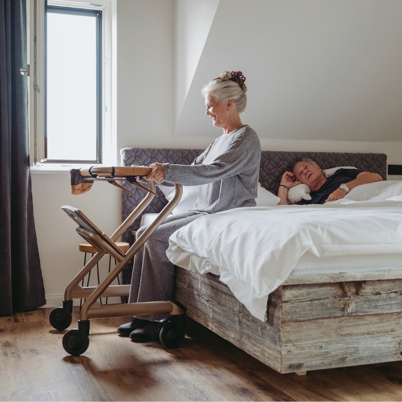 Femme assise au bord du lit en s'appuyant sur le rollator d'intérieur Saljol - réf. 826307BL