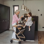 Femme âgée debout dans sa cuisine avec le rollator d'intérieur Saljol et son plateau, une petite fil