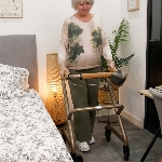 Femme marchant dans une chambre avec le rollator d’intérieur Saljol, adapté aux espaces restreints -