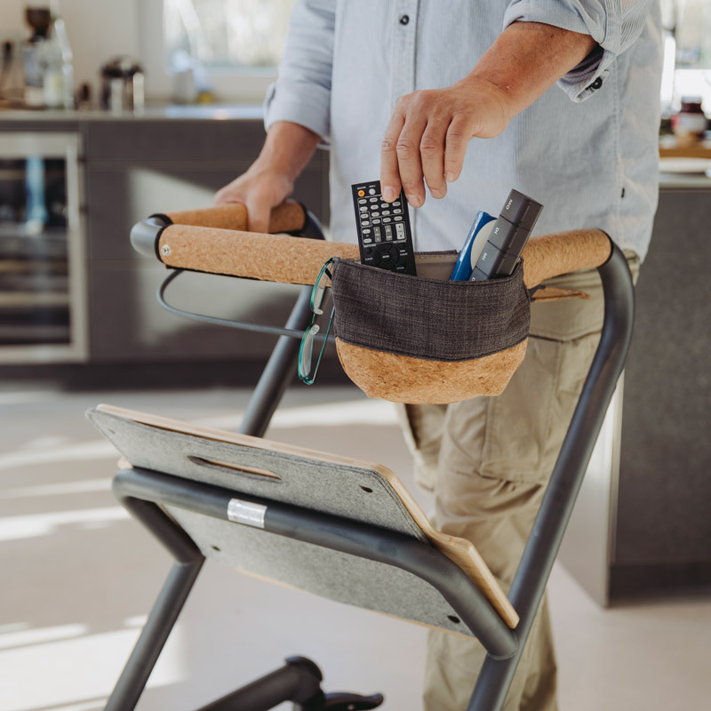 Homme prenant une télécommande dans la sacoche du rollator d'intérieur Saljol dans une cuisine - réf